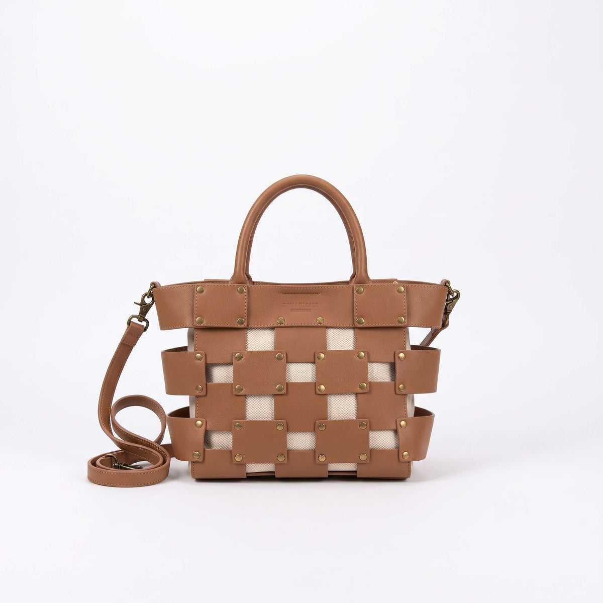Vista frontal de catálogo del bolso modelo Siena de piel color marrón (30x20 cm) sobre fondo blanco. Destaca su diseño exterior de tiras entrelazadas con remaches dorados y una correa larga enrollada en el lateral izquierd